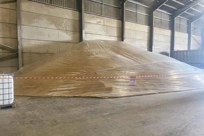 Sealed grain bulk with a fumigation danger sign and red-and-white safety barrier tape